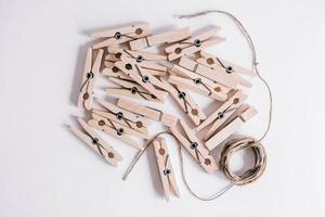 Wooden clothespins and rope on white background photo