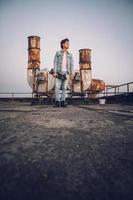 Man with skateboard on a background of rusty pipes photo