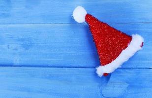 decoraciones de gorro de Papá Noel sobre fondos de madera de color azul pastel arriba para el concepto de vacaciones de Navidad foto