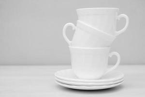 White ceramic cups with saucers on white table photo