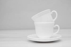 White ceramic cups with saucers on white table photo