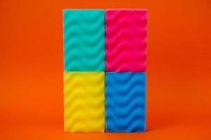 Multicolored sponges for cleaning on a orange background photo