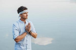 Man holding hands in prayer on background water reflex of blue sky photo