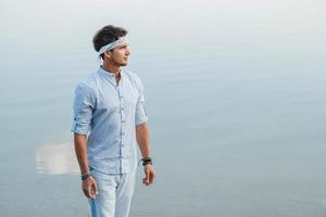 Man dressed in light clothes looks at water photo