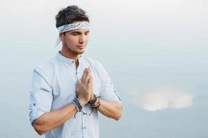 Man holding hands in prayer on background water reflex of blue sky photo