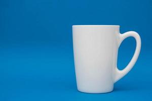 White ceramic cup on blue background photo