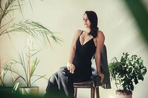 Woman dressed in black clothes sits on a chair in loft style interior photo