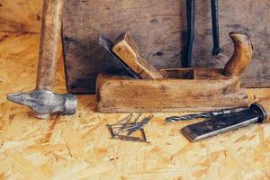 Antiguas herramientas de construcción en un banco de trabajo de madera de fondo plano laico foto