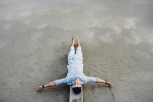 Man lying on wooden bridge against background of water photo