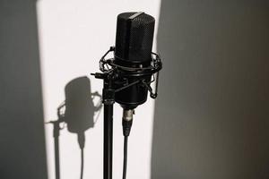 Micrófono de estudio profesional en un trípode moderno, muy conveniente y práctico. fondo blanco con sombra en la pared