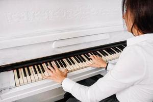 Bella mujer vestida con vestido blanco tocando el piano blanco