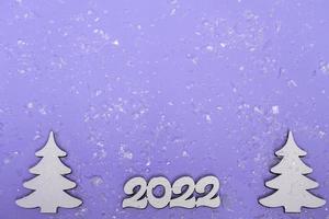 Merry Christmas and Happy New Year. Festive poster with a Christmas tree, sleighs on a purple background with lights. New year 2022 copy space close up photo