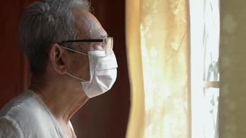 Elderly man wearing face mask by the window video