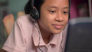 adorável garota feliz usando fone de ouvido conversando com seus amigos com videochamada via webcam do computador.
