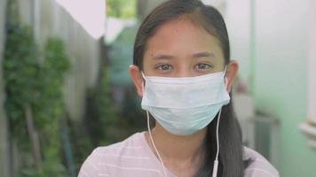 Retrato de niña con una máscara protectora y escuchando música video