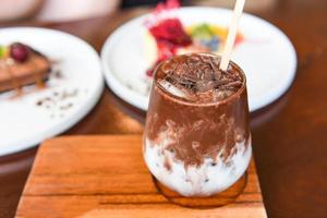 cocoa drink and chocolate - tasty milk shake with ice cocoa in glass on wood background photo