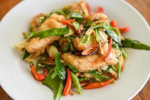 Thai food stir fried fish with pepper chili and herb on white plate - Tilapia fish cooked food photo