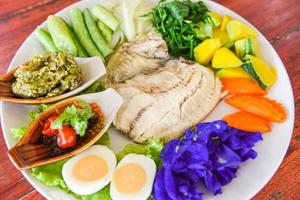 Steamed fish with chili sauce boiled eggs and vegetables pumpkin carrot on white plate - Thailand food Asian cooked tilapia fish photo