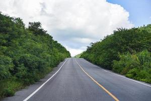 Camino a la montaña: un camino largo y recto que conduce hacia un árbol verde de la naturaleza en las montañas, camino asfaltado en Tailandia foto