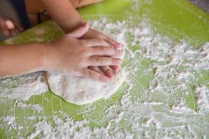 hands knead the dough homemade pastry for bread or pizza Bakery background - child hands prepares the dough with flour on board photo