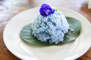 El arroz azul y la flor de guisante de mariposa para la salud de los alimentos naturales - palomas asiáticas con arroz tailandés cocido en hojas verdes en la placa foto