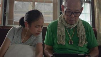 Großvater und seine Enkelin schauen sich soziale Videos auf einem digitalen Tablet an.