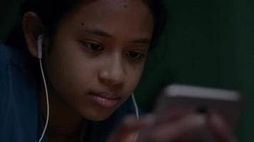 Teenager-Mädchen, die nachts soziale Videos online auf dem Smartphone ansehen.