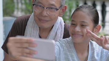 Teenager-Mädchen und ihr Großvater machen ein Selfie-Video.