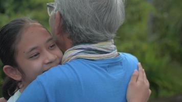 Granddaughter hugging her grandfather in the garden. video
