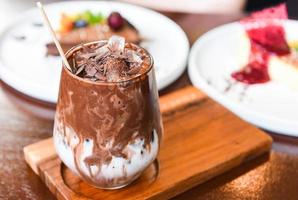 cocoa drink and chocolate - tasty milk shake with ice cocoa in glass on wood background photo