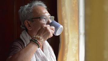 älterer Mann, der Kaffee trinkt, während er aus dem Fenster schaut