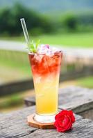 tea flowers made from tea rose petals in a glass on wooden table and nature green background - Iced tea with a tea rose Cold cocktail photo