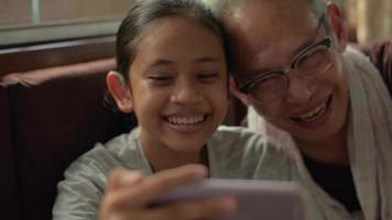 A girl with her grandfather talking with people on a video call