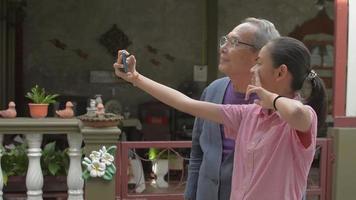 chica alegre tomando selfie con su abuelo en casa. video