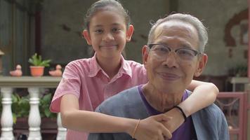 Portrait of smiling girl hugging her grandfather and looking at camera. video