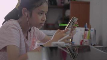 Jovencita usando audífonos y estudiando en línea en un teléfono inteligente video