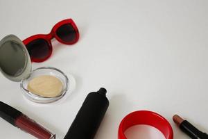 Cosméticos femeninos, perfumes y gafas de sol rojas. foto