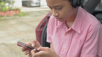 niña de la escuela secundaria usando audífonos y jugando juegos en el teléfono inteligente video