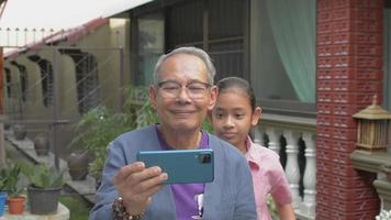 Grandfather taking selfie with granddaughter at home.