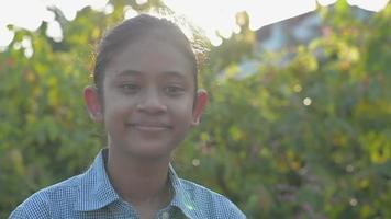 Smiling girl looking at the camera while standing in the courtyard under morning sunlight. video