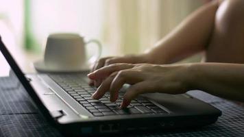 Woman's hands typing on a computer and drinking coffee video