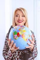 Hermosa mujer rubia sonriente alegre agente de viajes sosteniendo el globo en sus manos