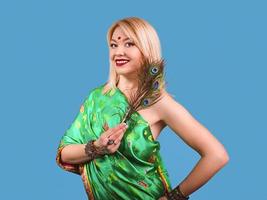 Hermosa mujer rubia caucásica atractiva sonriente en traje nacional indio con plumas de pavo real, pulseras, accesorios. viaje foto