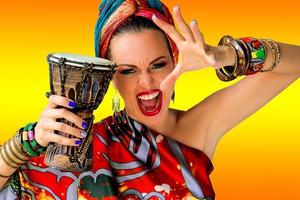 portrait of screaming young attractive woman singer in african style with drum on colorful background