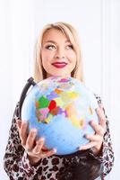 beautiful cheerful smiling blonde woman travel agent holding globe in her hands photo