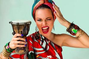 portrait of screaming young attractive woman singer in african style with drum on colorful background photo