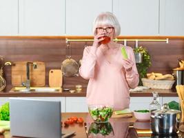 Blogger de video de mujer alegre senior mostrando jugo de tomate y apio en su cocina. crudo, vegetariano, dieta, blogger, concepto de cocina nutricionista foto