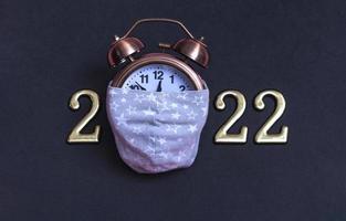 Alarm clock with gold numbers on a black background. Minimal concept of the new year 2022 photo