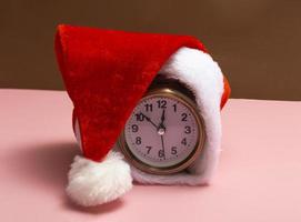 Alarm clock with santa hat on a colored background. New year shopping concept. Close up with copy space photo