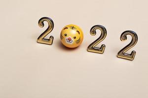 New year concept golden numbers 2022 with tiger face on beige background with copy space photo